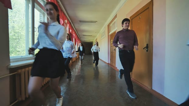 A down-syndrome school boy with group of children in corridor, running.