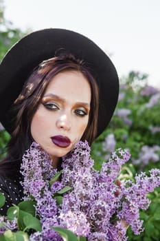 A fashionable girl with dark hair, a spring portrait in lilac tones in summer. Bright professional makeup