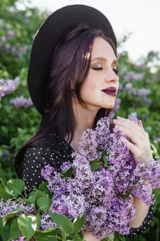 A fashionable girl with dark hair, a spring portrait in lilac tones in summer. Bright professional makeup