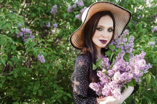 A fashionable girl with dark hair, a spring portrait in lilac tones in summer. Bright professional makeup