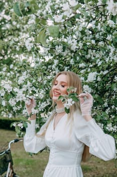 A blonde girl with long hair on a walk in a spring park. Springtime and blooming apple trees