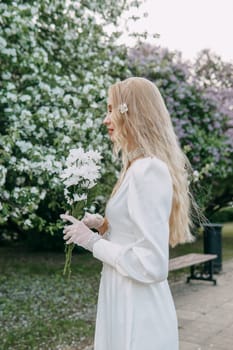 A blonde girl with long hair on a walk in a spring park. Springtime and blooming apple trees