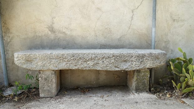 A light granite bench along the wall of an old abandoned house.