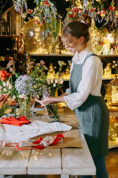A woman in her florist shop collects bouquets of flowers. The concept of a small business. Bouquets of tulips for the holiday on March 8
