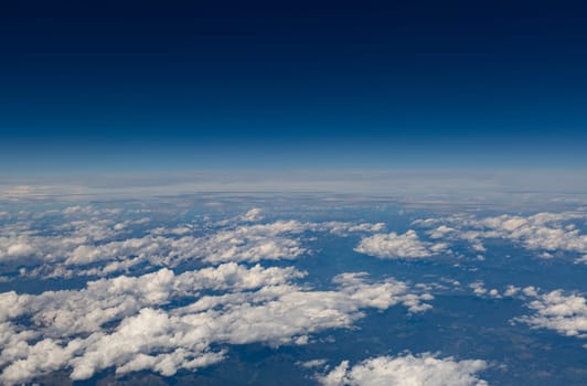 Beautiful view of white clouds above the ground through a porthole window against the background of a blue sky, close-up side view.