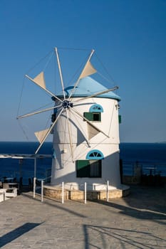 Beautiful view of the blue and white mill in the Greek style on a sunset summer evening, close-up side view.