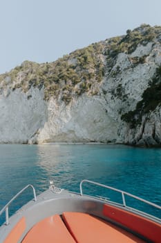 Beautiful panoramic view of a green mountain island in the blue sea with the bow of a boat on a sunny summer day, close-up side view.