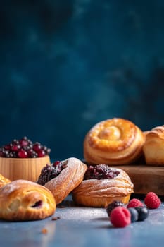 Assorted sweet pastries with berries on a dark background