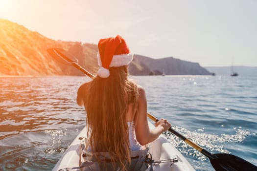 Woman in kayak back view. Happy young woman with long hair floating in transparent kayak on the crystal clear sea. Summer holiday vacation and cheerful female people relaxing having fun on the boat