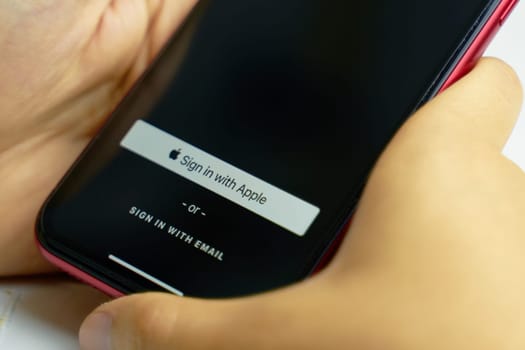 Bishkek, Kyrgyzstan - June 6, 2019: Sign in with Apple Button for your privacy. Man holds a smartphone and authorizes the Internet service