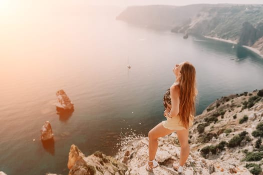 Woman travel sea. Happy tourist taking picture outdoors for memories. Woman traveler looks at the edge of the cliff on the sea bay of mountains, sharing travel adventure journey.