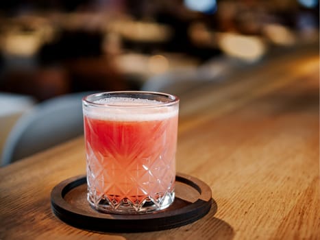 Glass of fresh pink grapefruit juice on bar counter in restaurant interior. Delicious cold fresh grapefruit juice or cocktail in bar or nightclub. Copy space