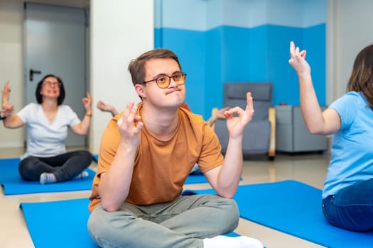 Man with down syndrome practicing lotus pose in yoga class next to friends with special needs