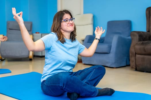 Woman with special needs enjoying during yoga class sitting in lotus position and arms raised