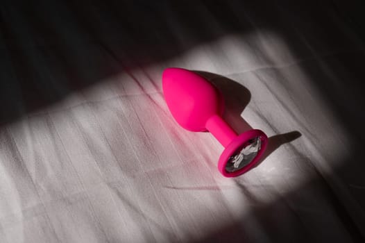 Pink silicone anal plug on a white sheet