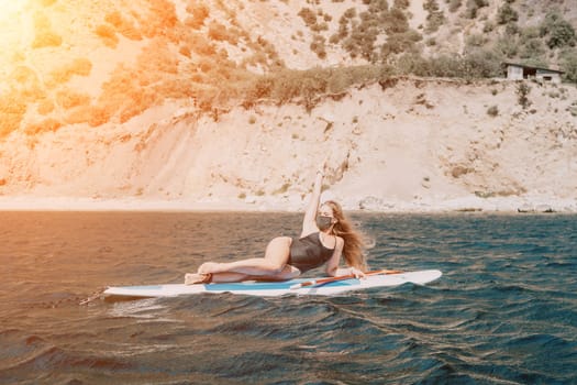 Close up shot of beautiful young caucasian woman with black hair and freckles looking at camera and smiling. Cute woman portrait in a pink bikini posing on a volcanic rock high above the sea