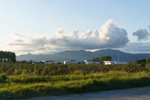 A dirt road stretches out in front of a majestic mountain range, showcasing the rugged beauty of the natural landscape.