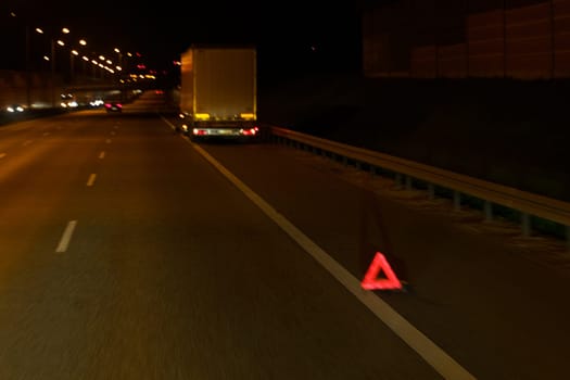 A red triangle sign is placed on the side of a road, alerting drivers to potential hazards or upcoming road conditions.