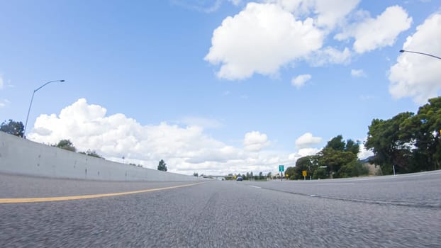 On a clear winter day, a car smoothly travels along Highway 101 near Santa Maria, California, under a brilliant blue sky, surrounded by a blend of greenery and golden hues.