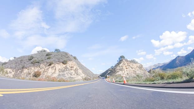 Vehicle is cruising along the Cuyama Highway under the bright sun. The surrounding landscape is illuminated by the radiant sunshine, creating a picturesque and inviting scene as the car travels through this captivating area.