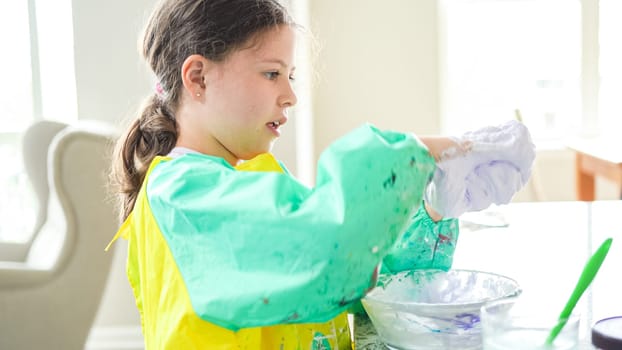 In a modern kitchen, a homeschooled girl is engrossed in creating homemade slime, a fun and educational hands-on project that enhances her creativity and problem-solving skills.