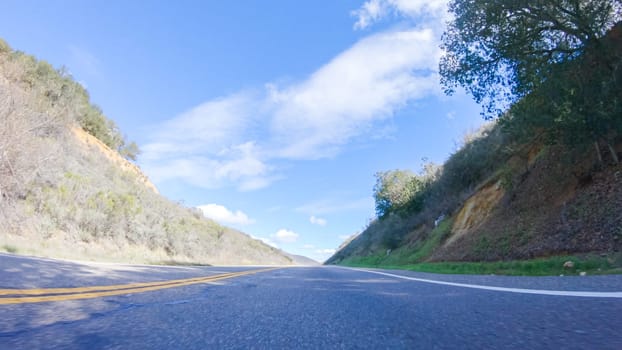 Vehicle is cruising along the Cuyama Highway under the bright sun. The surrounding landscape is illuminated by the radiant sunshine, creating a picturesque and inviting scene as the car travels through this captivating area.