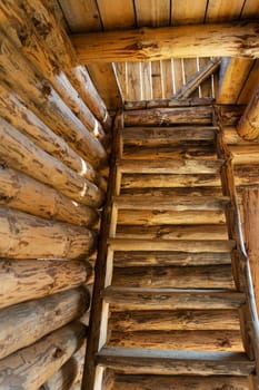 Rustic old wooden staircase inside a log cabin in warm colors and textures