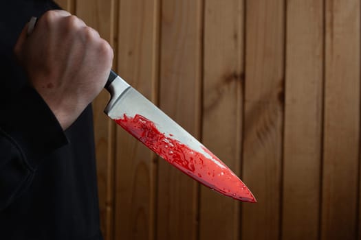 Bloody knife in hand with reverse grip, criminal holding murder weapon