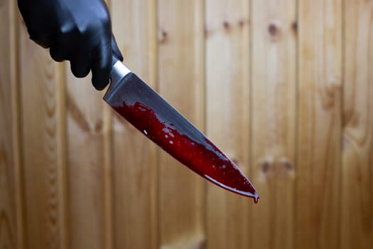 Killer holds bloody knife in his hand, drops of blood flowing down on the murder weapon in the hand of maniac