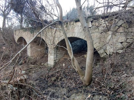 old abandoned stone bridge with arches in the forest.