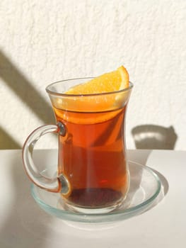 black tea with lemon in a glass cup and saucer in the sunlight.