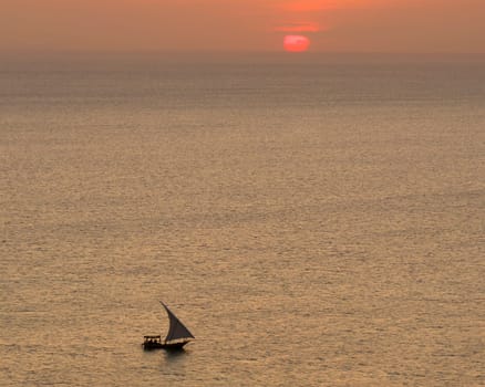 african boat sails in the ocean at sunset,background wonderful red sun, summer concept Zanzibar, Tanzania.