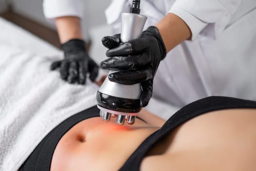 A skilled cosmetologist doing RF skin tightening and body contouring treatments to enhance the youthful allure of a clients abdomen.