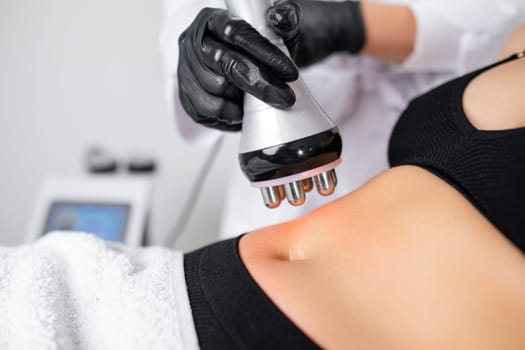 RF body cavitation lifting procedure to reduce fat in belly to young woman in a beauty salon