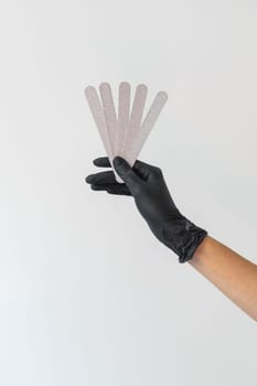 Female hand holds nails files on white background. Concept of polishing nails. Spa treatment beauty. White background with copy space