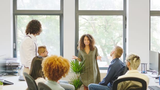 Female boss talking to her employees in the office. Coworking