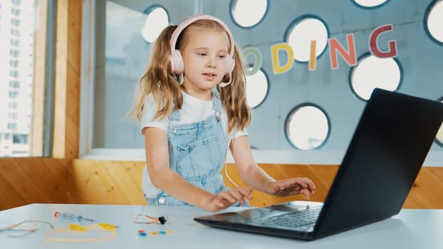 Young student working on laptop or studying in online classroom. Caucasian girl typing on laptop while doing homework or listening music.Little kid wearing headphone. Creative learning. Erudition.