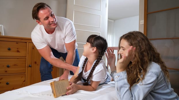 Bedtime story with childhood storytelling, mom and dad reading a fantasy book together to their little young girl in cozy and comfortable bedroom. Modern family happy time. Synchronos