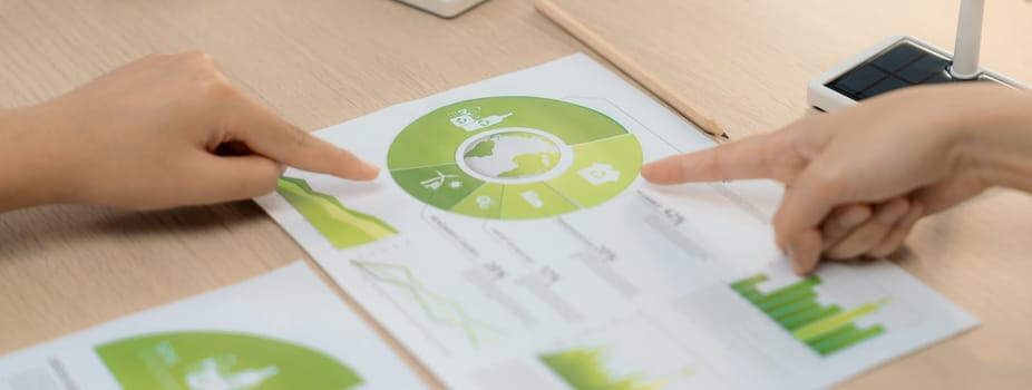 Rising graph representing the profit of using clean energy, displayed on a table at a green business meeting. Environmental documents was scattered around the table. Closeup. Delineation.