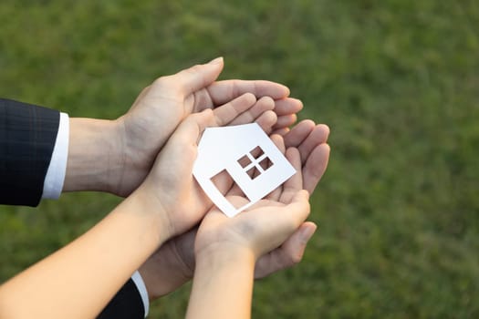 Businessman hold house icon together with child's hand, presenting house loan opportunity as part of real estate sales. Promoting eco-smart homes, embodying vision for sustainable future. Gyre