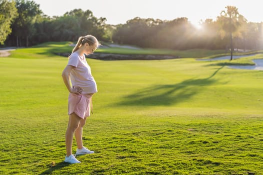 Energetic pregnant woman takes her workout outdoors, using an exercise mat for a refreshing and health-conscious outdoor exercise session.