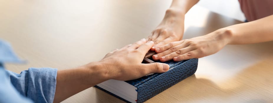 Close-up women prayer deliver holy bible book and holy cross to male believer. Spreading religion symbol. Concept of hope, religion, Christianity and god blessing. Warm background. Burgeoning.