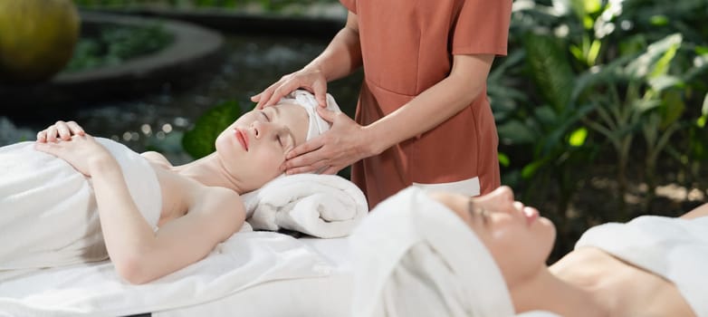 A portrait of two caucasian woman with beautiful skin having facial massage while falling the deep state of relaxation surrounded by outdoor natural and peaceful environment. Tranquility.