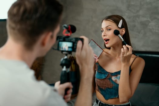 Man filming video on young woman making beauty and cosmetic tutorial video content for social media. Beauty blogger smiles to camera while showing how to beauty care to audience or follower. Unveiling