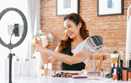 Asian Woman influencer shoot live streaming vlog video review makeup uttermost social media or blog. Happy young girl with cosmetics studio lighting for marketing recording session broadcasting online