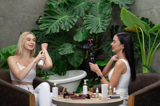 Two beautiful content creator making natural beauty and cosmetic tutorial on green plant garden video. Beauty blogger showing how to beauty care to social medial audience using selfie stick . Blithe