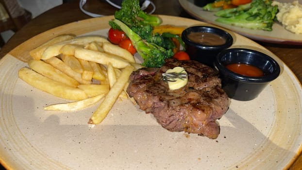 Juicy beef steak with salad and mashed potato along with pepper corn sauce served on wooden plate wooden stone table. Top view on a restaurant