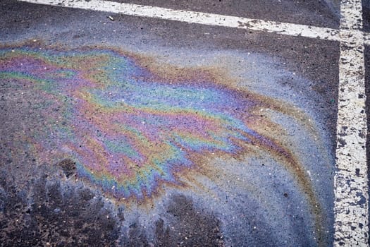Oil, gasoline, or oil spill on wet asphalt with a parking lot and a dividing line.