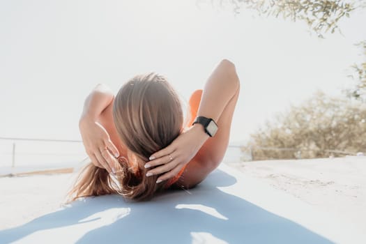 Fitness woman sea. Outdoor workout on yoga mat in park near to ocean beach. Female fitness pilates yoga routine concept. Healthy lifestyle. Happy fit woman exercising with rubber band in park.