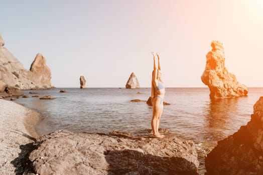 Middle aged well looking woman with black hair doing Pilates with the ring on the yoga mat near the sea on the pebble beach. Female fitness yoga concept. Healthy lifestyle, harmony and meditation.